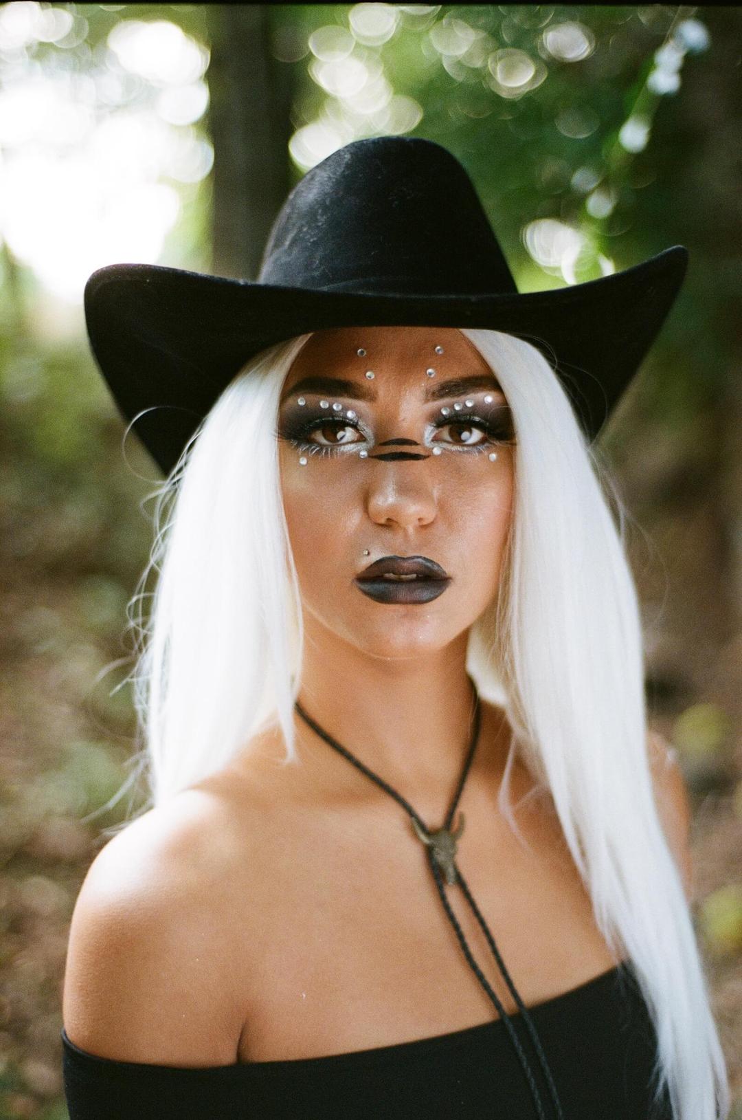 Woman with painted face and cowgirl hat.