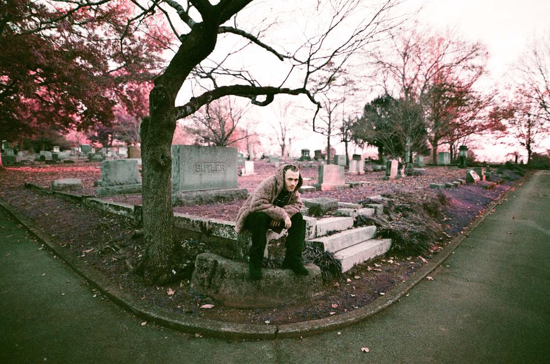 Man posing in front of a graveyard in Huntsville, AL