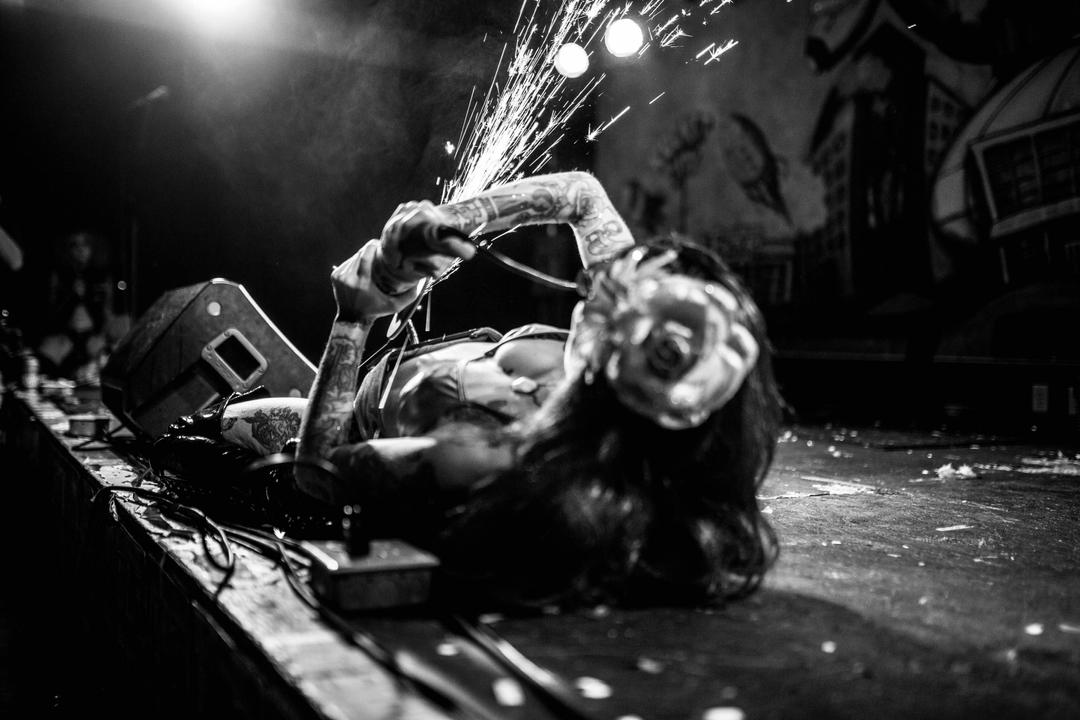 Live band performance. Performer laying on the ground and causing sparks with a saw